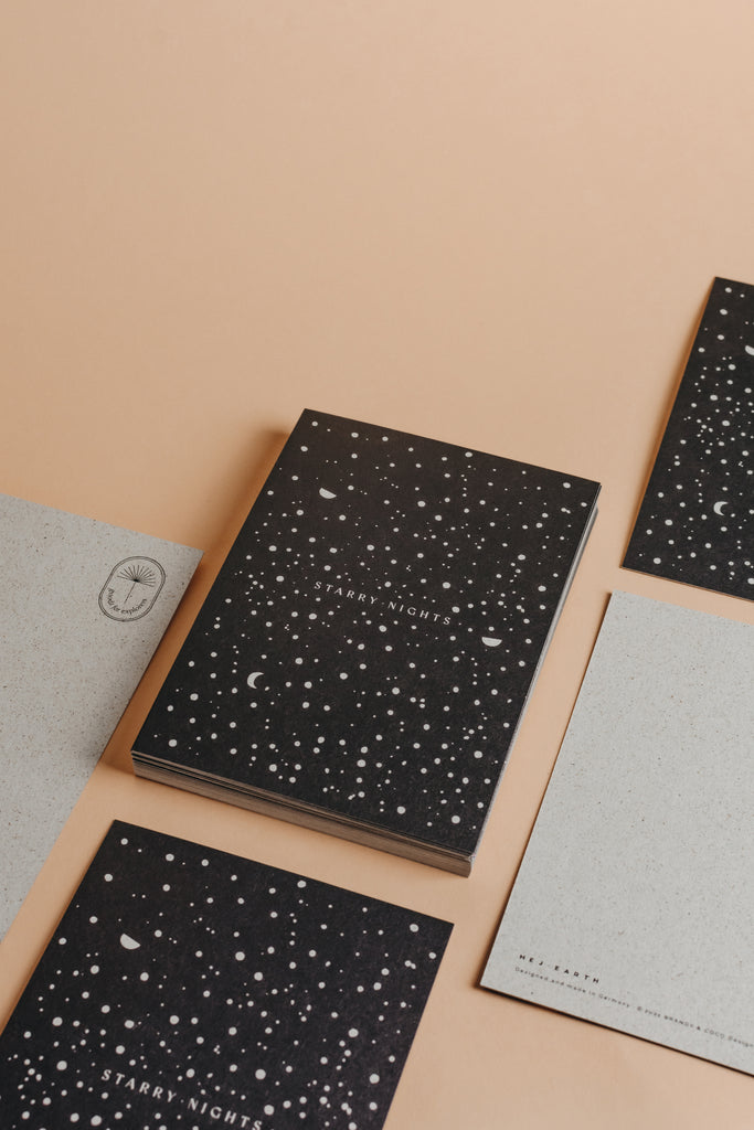 Starry nights postcard with black and light grey grass paper material and simple stars and moon motive.