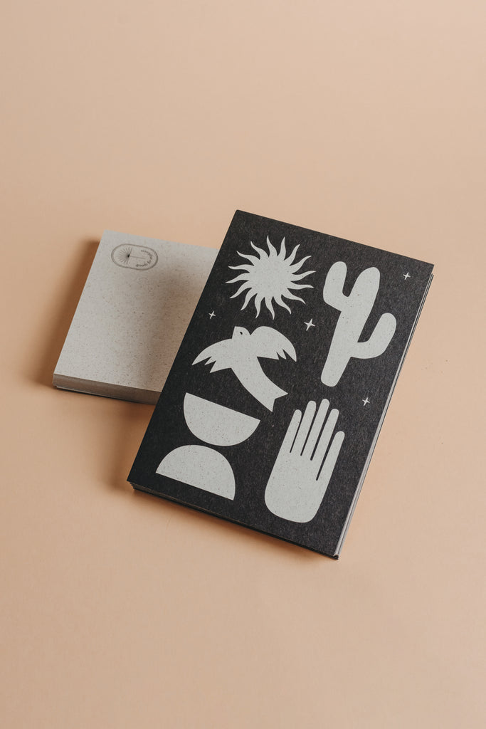 Bohemian postcard with black and light grey grass paper material and half moon, hand, bird, cactus and sun motive.